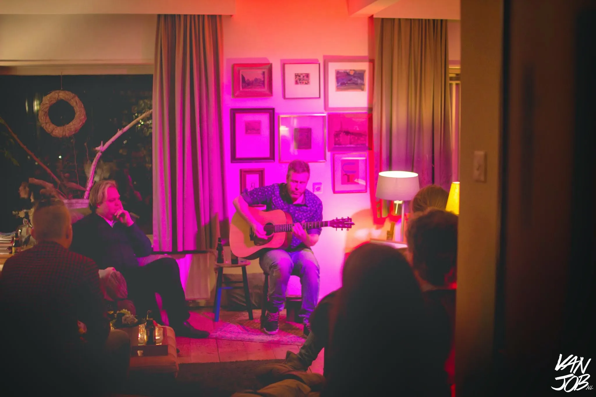 Intieme huiskamerconcert setting met publiek rondom de artiest